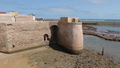 Ebb-outside-wall-of-moroccan-fortification,-sideways-pan