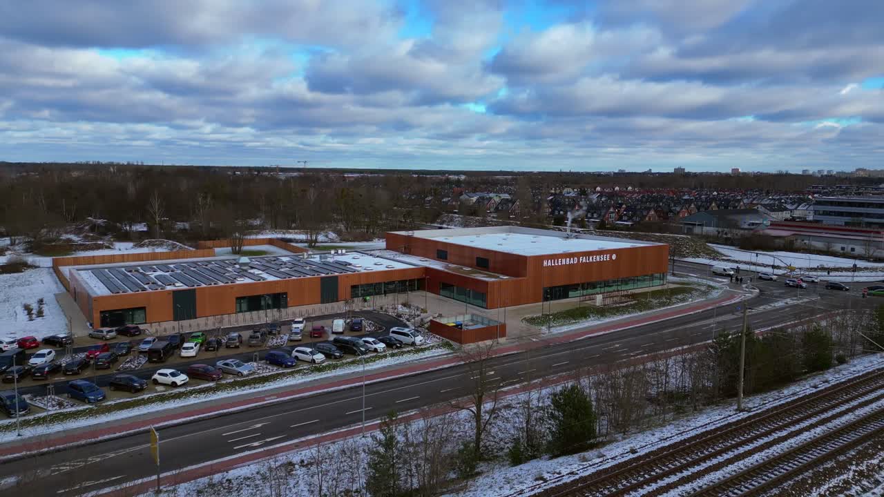 Indoor swimming pool with solar panels surrounded by snow and suburban homes in Falkensee Germany. Majestic aerial view flight panorama orbit drone