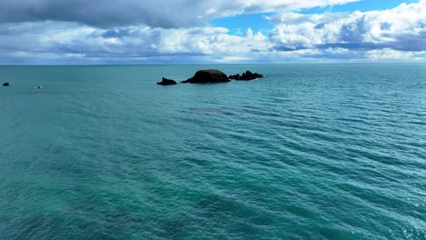 Drone-Volando-Bajo-Y-Lento-Sobre-Mares-Verde-Esmeralda-Con-Un-Cielo-Espectacular-En-El-Horizonte-Costa-De-Waterford-Irlanda