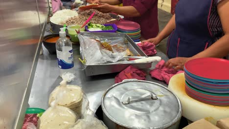 Mexican-Woman-Adding-Toppings-To-Street-Tacos-Plate-In-Street-Taco-Stand-During-Night-Time-In-Busy-Urban-Area