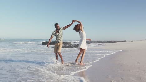 african american couple walking seaside and kissing