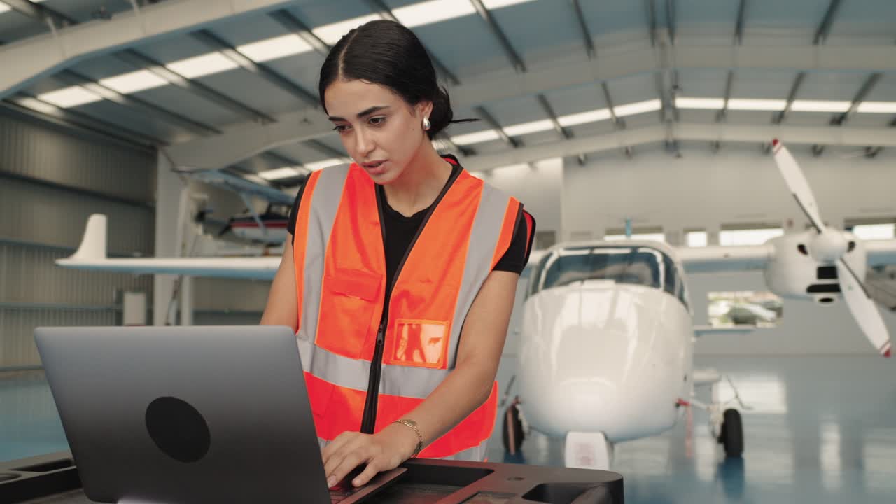 Aircraft mechanic working on a laptop in an airplane hangar