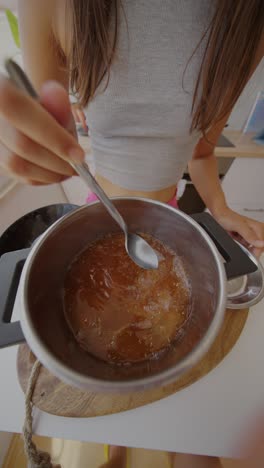 person stirring homemade jam in a pot in the kitchen