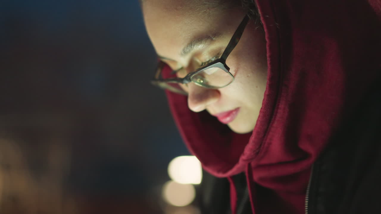 Evening Reading Scene, Quiet Urban Bench Illuminated By Screen Glow, Person In Red Hood Engrossed In Phone Reading At Dusk, Peaceful City Park Scene With Warm Screen Lighting And Reflective Mood