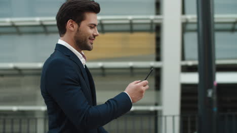 Side-view-businessman-using-phone.-Businessman-walking-in-luxury-suit-outside