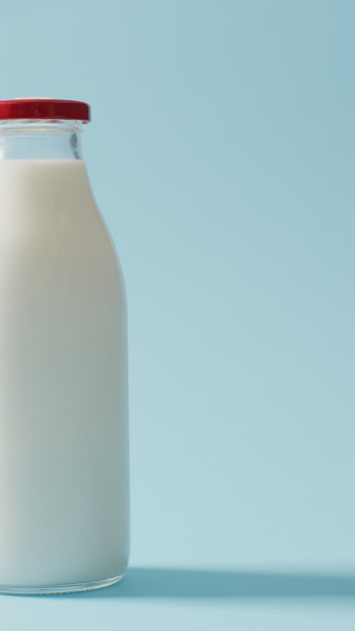 video vertical de una botella de leche antigua sobre un fondo azul