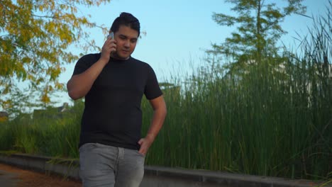 young man is having a phone conversation while walking in a suburban neighborhood