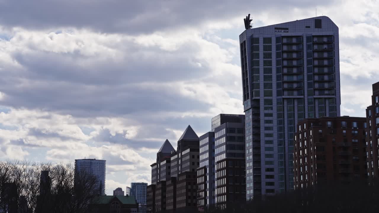 Contemporary high-rise apartments and office buildings in Jersey City stand tall beneath a dramatic cloudy sky