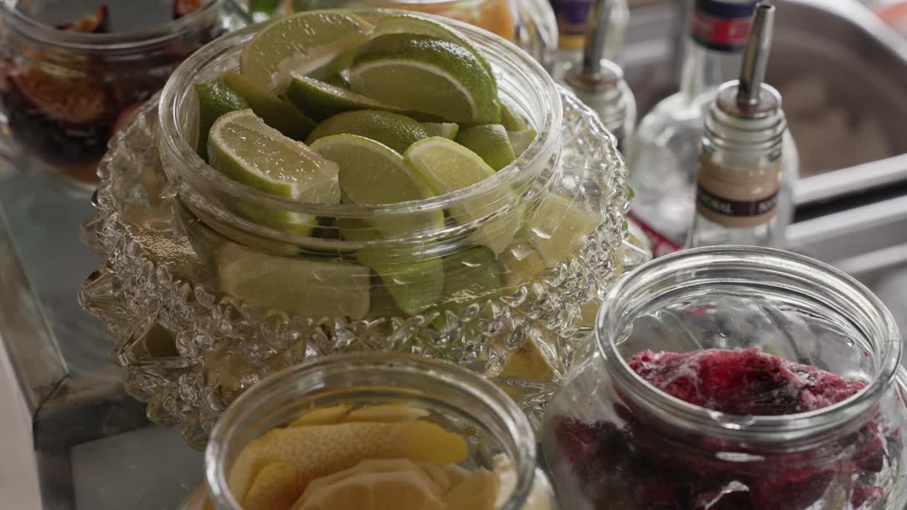 lemon lime and frozen berries in jars prepared for fresh cocktail garnishes