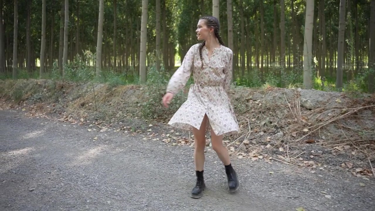 Una donna che fa una passeggiata rilassante nella natura, dove la moda incontra perfettamente la serenità e la pace.