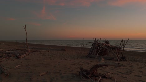 scenic driftwood tipi on a sandy beach during sunset