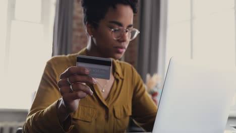 african woman holds credit card use laptop do online shopping