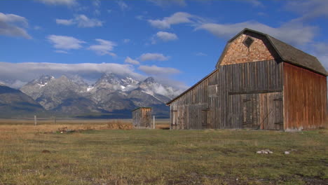 an old barn rises out of a prairie with the grand tetons in the background 9