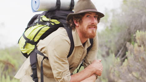 portrait of happy bearded caucasian male survivalist with backpack, enjoying wilderness scenery