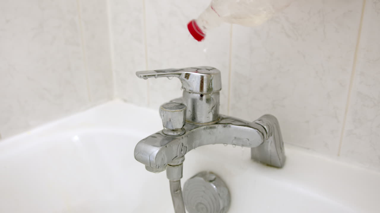 Close up of vinegar being poured over bathtub faucet for sanitation and cleaning