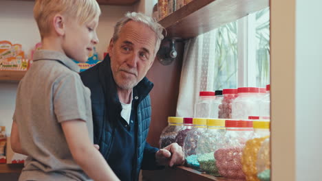 grandfather and grandson looking at jars of candy in a candy store