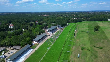 jockeys on racehorses on horse racing track, showcasing the vibrant green turf, stands filled with spectator landscape beyond. gorgeous aerial view flight speed ramp hyper motion time lapse