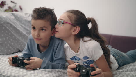 happy kids playing video game with joystick at home. friends play game console