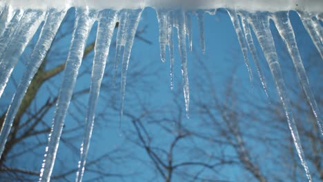 Eisstalaktiten,-Die-Von-Einem-Dachvorsprung-Hängen,-Von-Dem-Wasser-Tropft