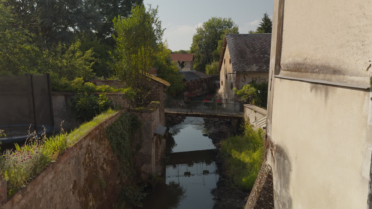 Picturesque view of Saint-Fargeau Town with narrow stream flowing under small bridge in France
