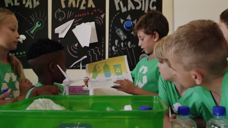 boy holding a poster about recyclable materials in the class