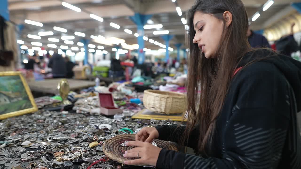 mujer explorando un puesto en el mercado de pulgas con joyas
