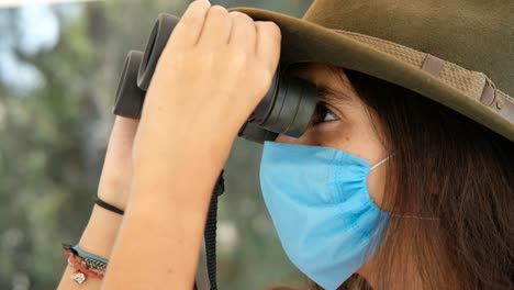 traveling tourist girl with bionoculars in a medical face mask