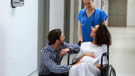 doctor and man interacting with pregnant woman in corridor