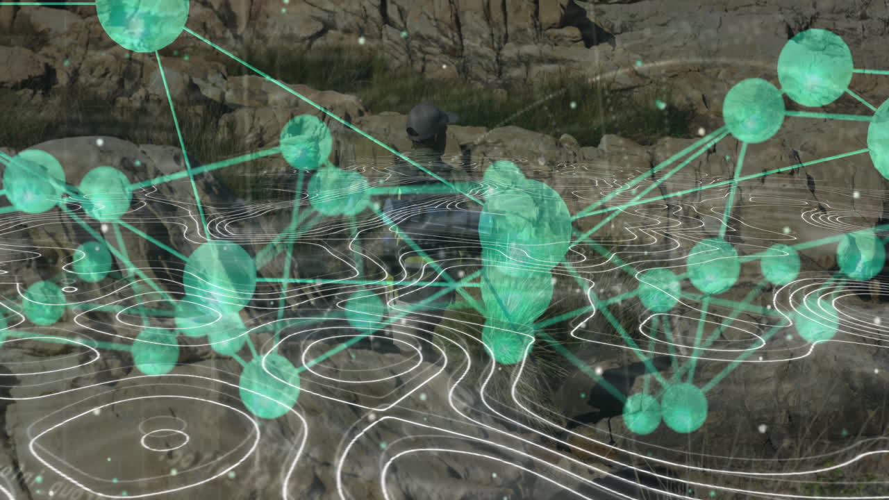 man wearing cap and backpack sitting on hill, viewing technology network nodes with contour lines