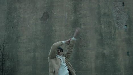 Stylish-Man-Dancing-Vogue-to-Camera-against-Old-Concrete-Building