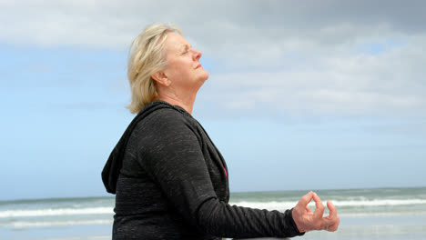 Vista-Lateral-De-Una-Anciana-Caucásica-Meditando-En-La-Playa-4k