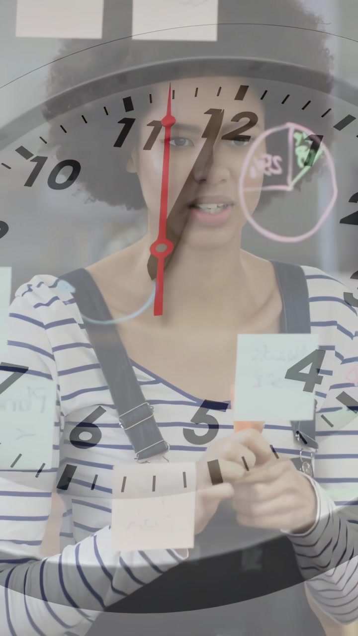 Video vertical: Mujer tomando un marcador, colocando notas en un cristal, etiquetando para planificación, reloj mostrando la hora.