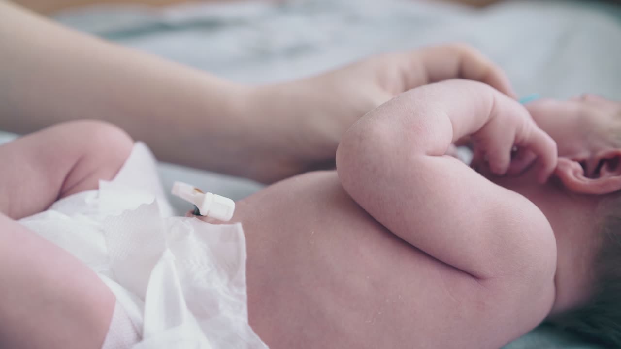 le mani della madre controllano l'ombelico vicino al pannolino sul bambino che piange