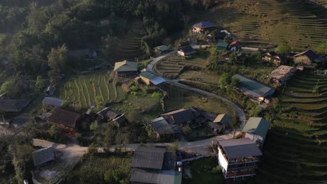 Aerial-drone-shot-of-villages-amdist-bright-green-rice-terraces-in-the-mountains-of-Sapa,-Vietnam