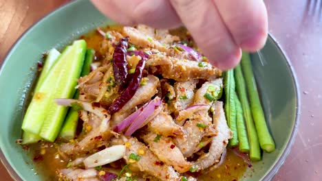 hand squeezing lime over spicy pork salad