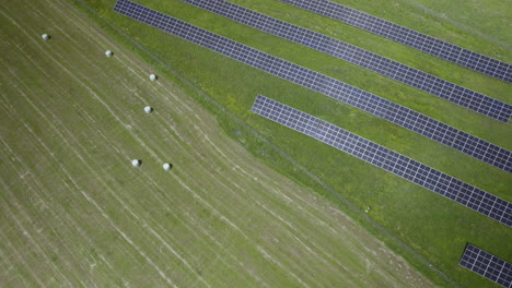Solar-Pv-Panels-installation-Array-Mounted-in-Green-Field-Land,-New-Source-of-Energy-and-Electricity-Technology-Modules,-Aerial-Descending-top-view