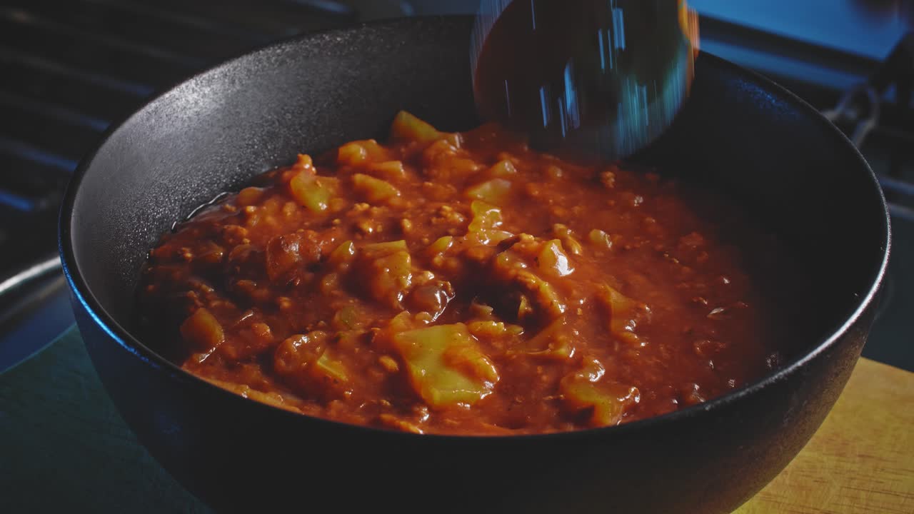 la cuchara de plata saca la comida del tazón negro en preparación para comer estofado de sopa