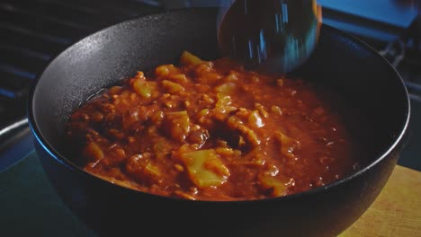 la cuchara de plata saca la comida del tazón negro en preparación para comer estofado de sopa