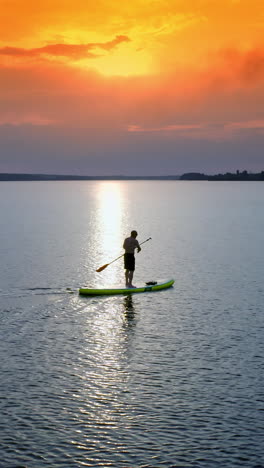 stand up paddle boarding. handsome young man standing on sup board