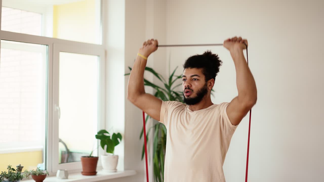 Mixed race sportsman is training arms with rubber bands