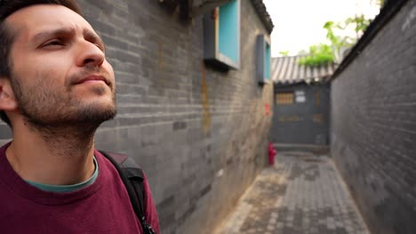 man exploring traditional siheyuan houses at jiuwan hutong in beijing, china