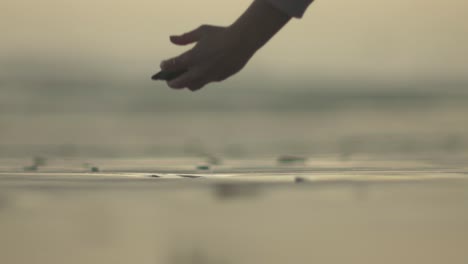 close up shot of a person picking up a stone on the beach during sunset or sunrise