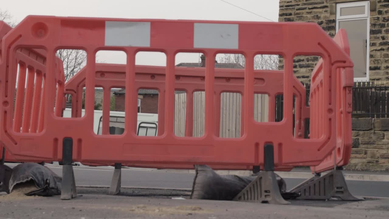 Hole in urban street surrounded by road crash barriers tilting shot