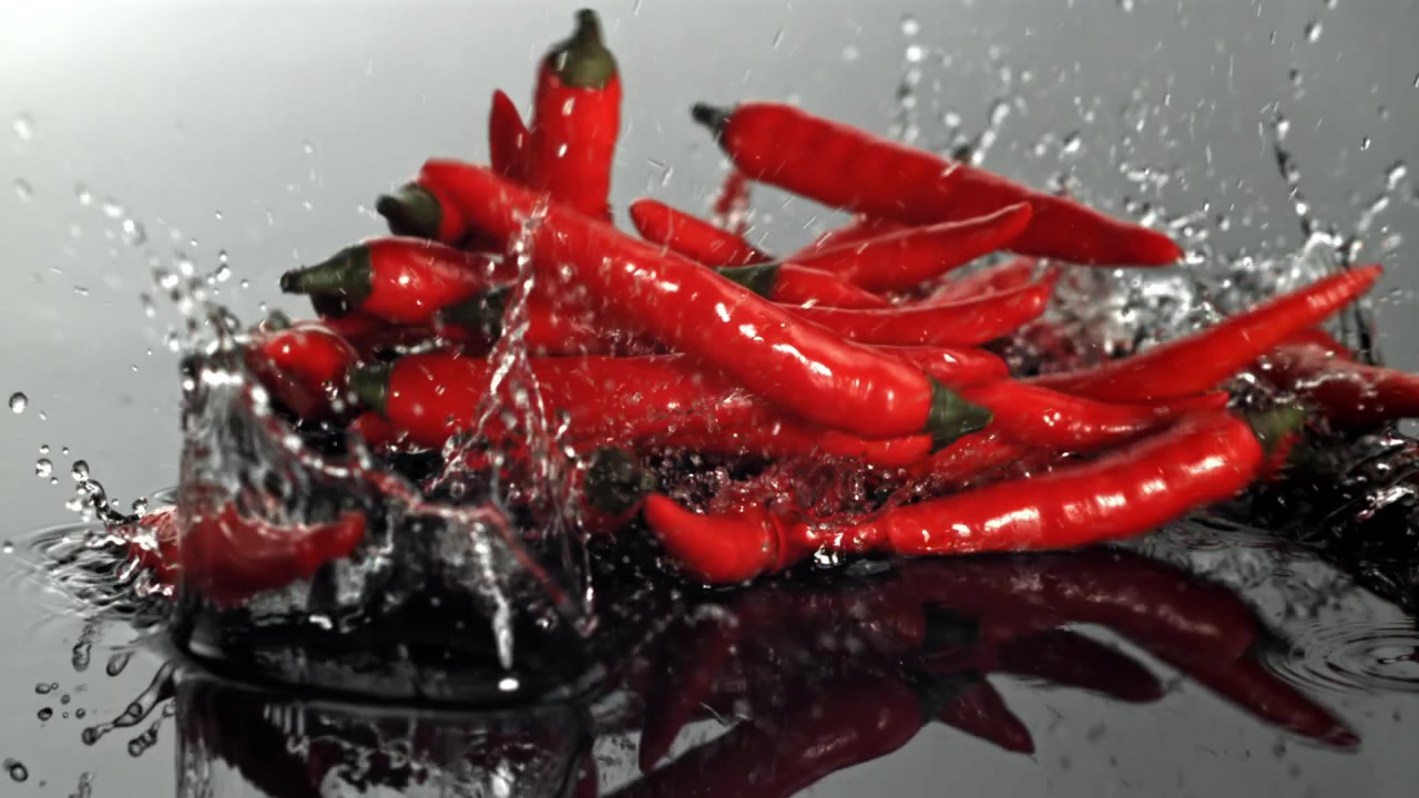 Fresh Red Chili Peppers Splashing into Water in Slow Motion