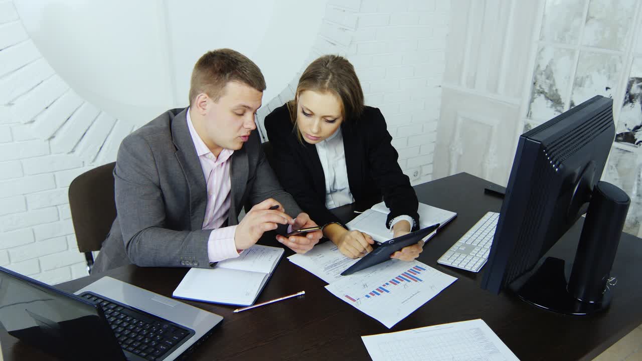 dos jóvenes socios empresariales emprendedores trabajan en una tableta en un estudio en el fondo de una ventana redonda