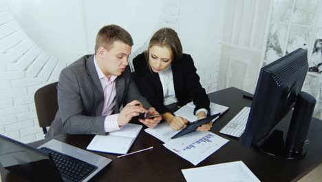 two young enterprising business partners work on a tablet in a study on the background of a round window