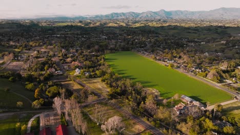 Aerial-Footage-Over-Farm-Fields-and-Houses-in-Quaint-Santa-Ynez,-California,-Central-Coast-Rural-Countryside-with-Mountains-on-Horizon