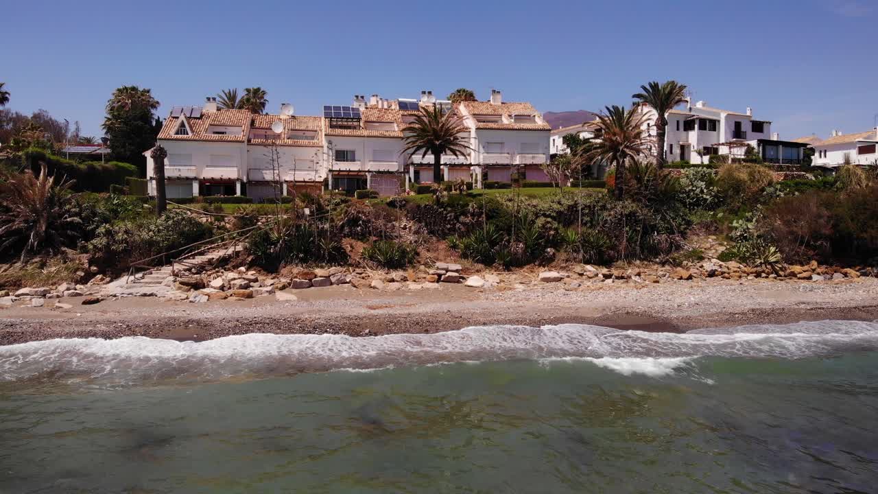 vista aérea de las olas del mar rompiendo en la playa con vistas a las villas de vacaciones en estepona, costa del sol