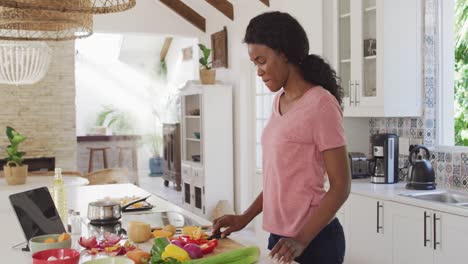 Video-of-happy-african-american-woman-preparing-meal-in-kitchen