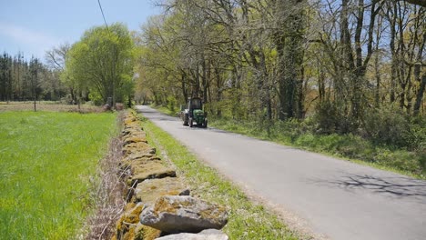 tracktor driving on road through the green countryside meadows on a beautiful summer day